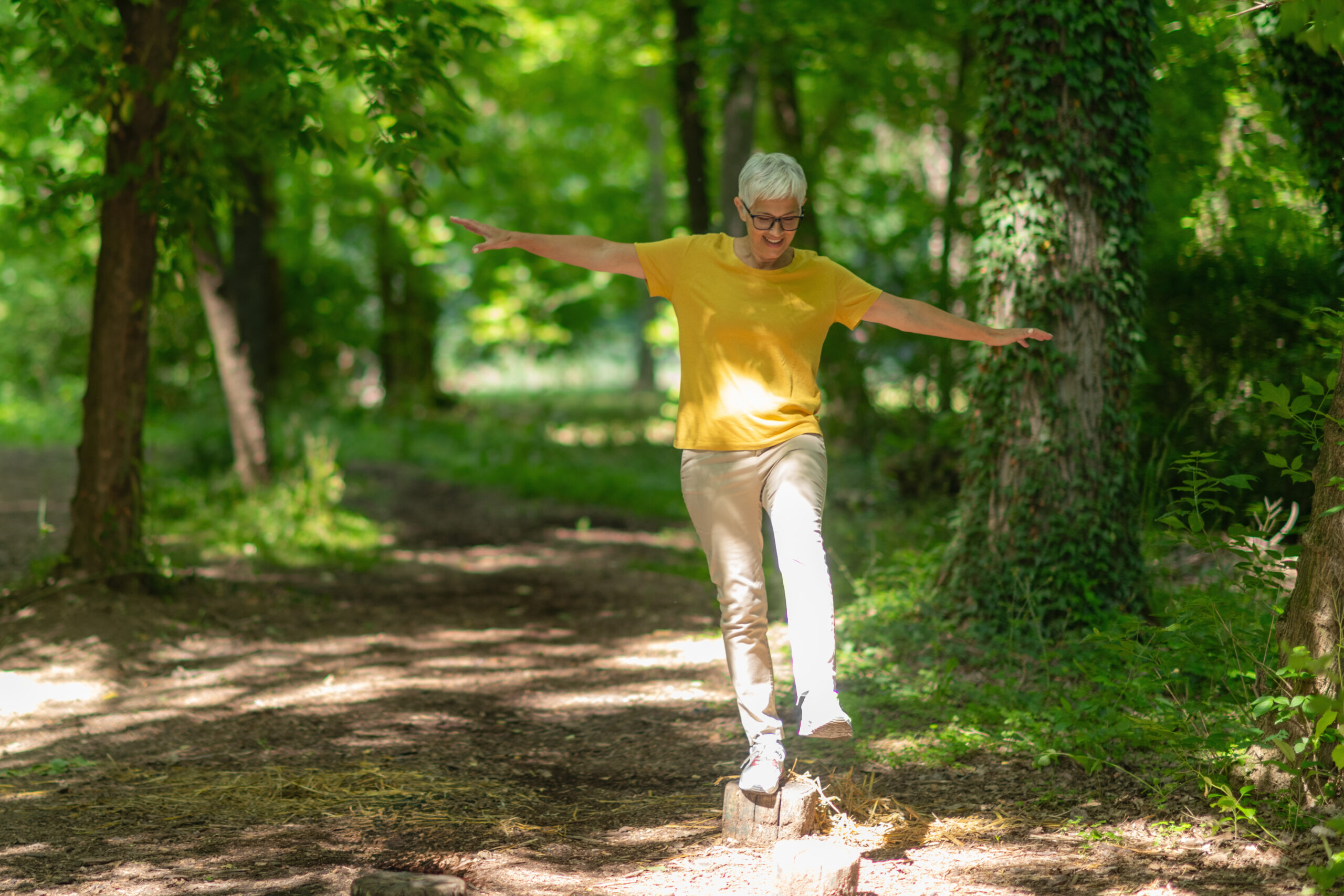 Senior woman doing balance exercises in the park to maintain agility and stability.
